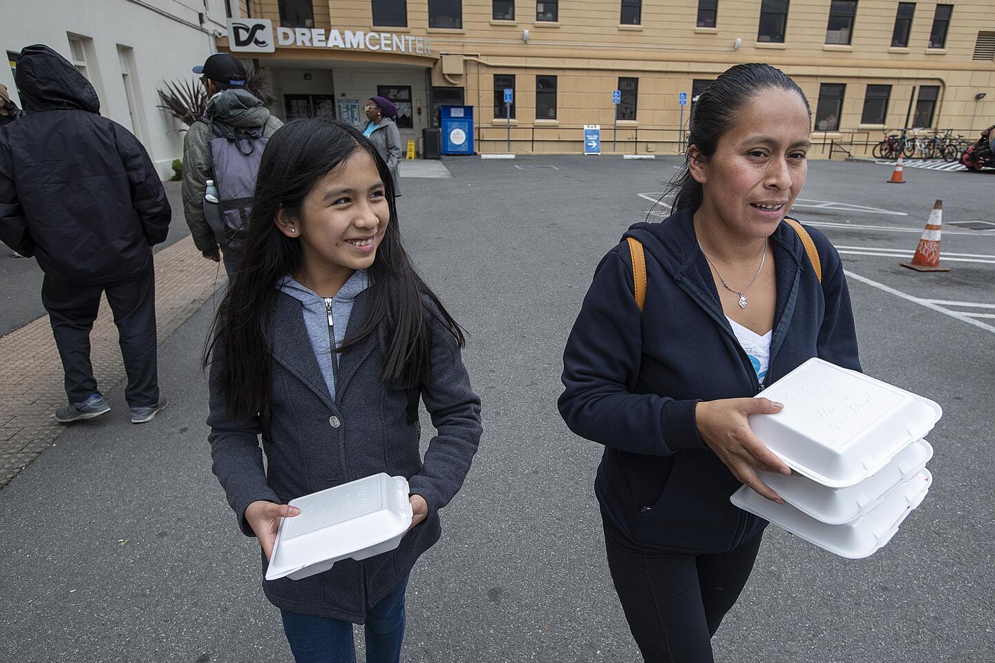 Karyna Renoj, 11, and her mom, Pascuala Reno, carry box lunches.