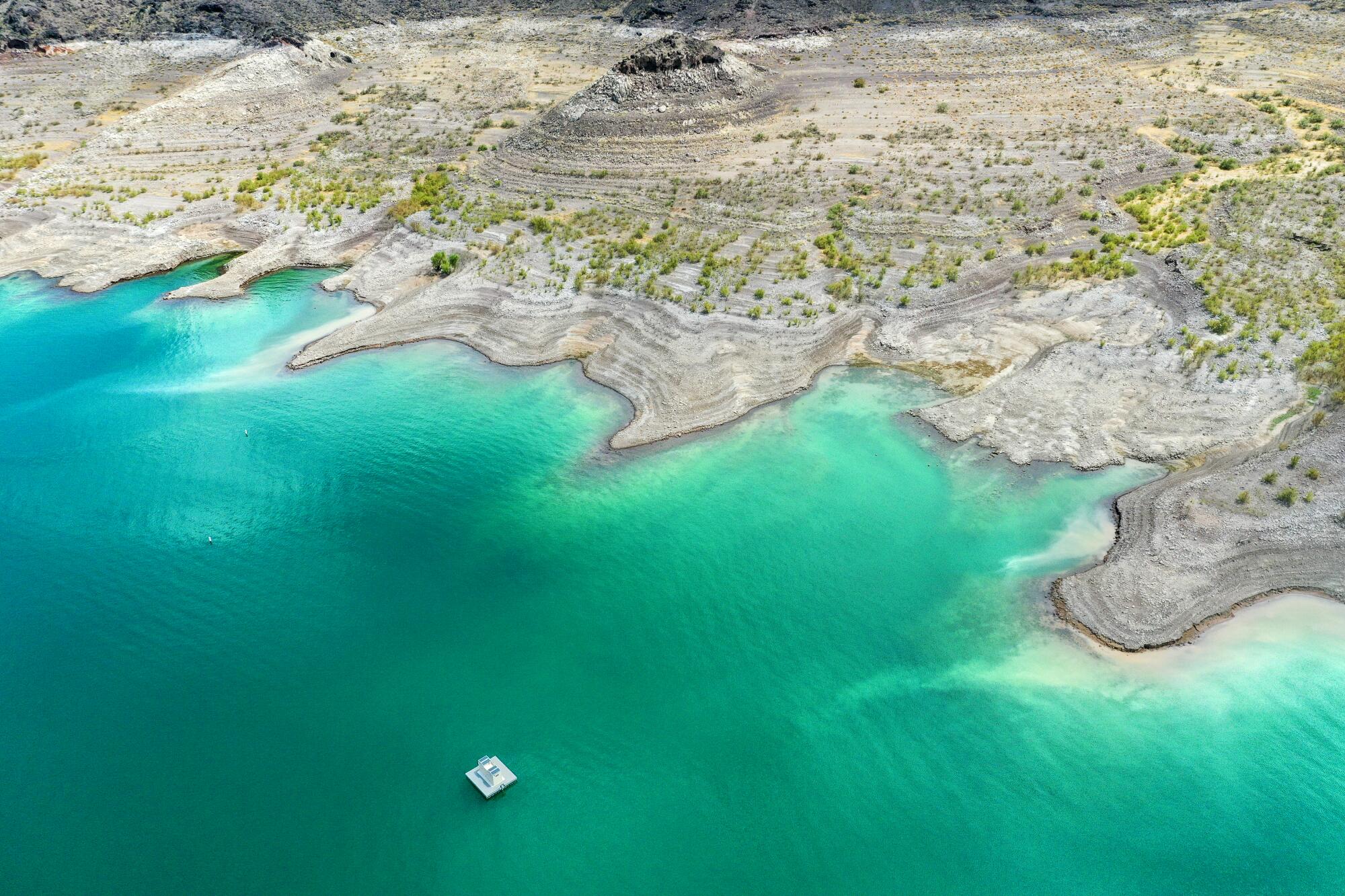 A green lake contrasts with a barren desert landscape