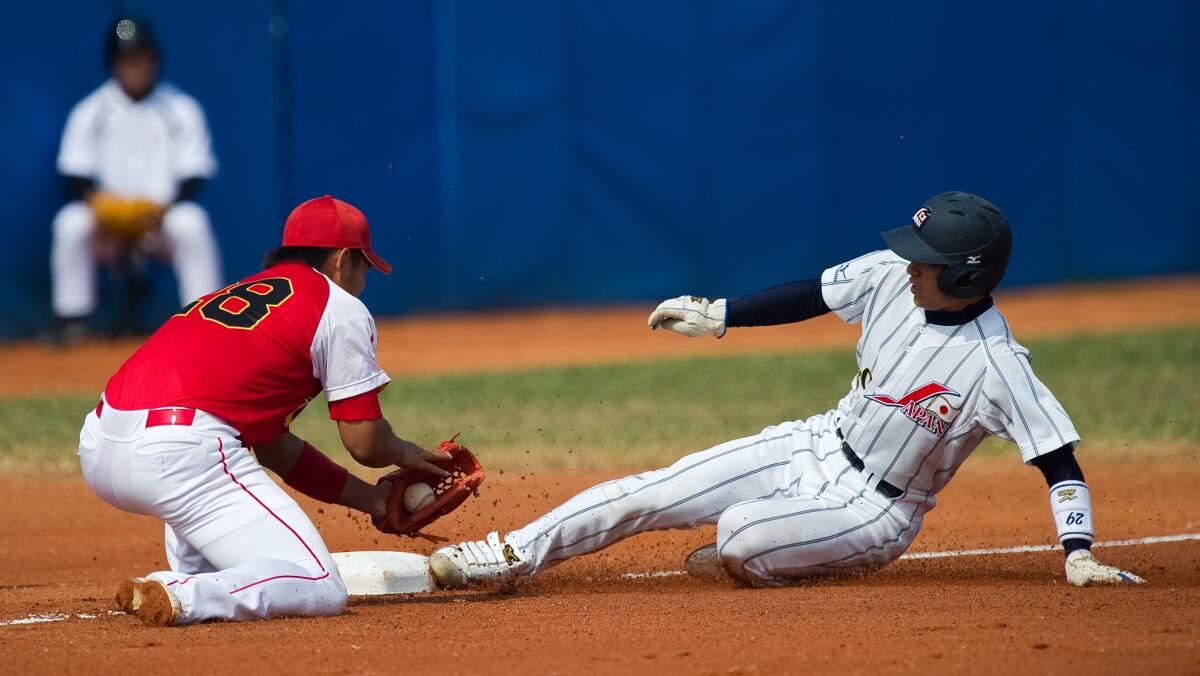 Japan's Hayata Ito slides safely into third base under the tag of China's Hao Guochen during the 2010 Asian Games.