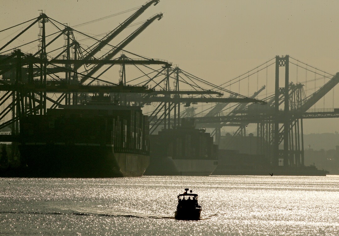 A tour boat drives past ships unloading freight containers