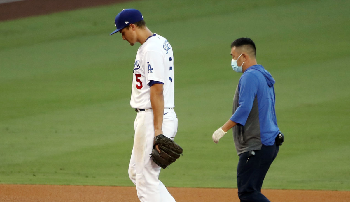 Dodgers shortstop Corey Seager walks off the field with a team trainer.