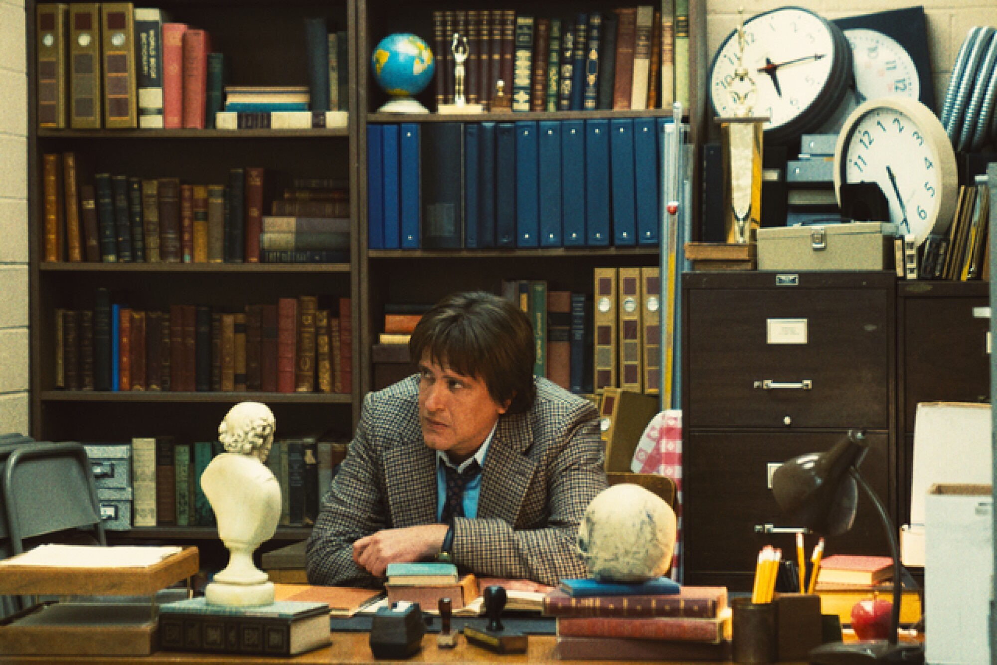 A professor in a tweed jacket slumps on his desk