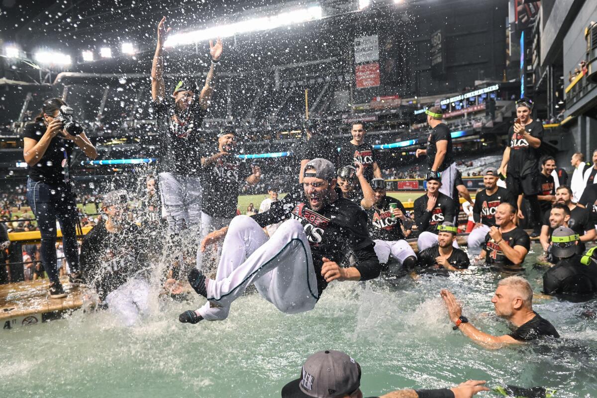Players on the Arizona Diamondbacks celebrate on the field and in the pool at Chase Field after defeating the Dodgers in the NLDS on Wednesday night.