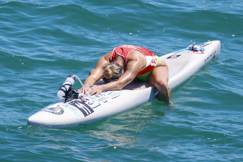Liz Hunter rests on her paddle board after winning the Catalina Classic Paddleboard Race at Manhattan Beach on Sunday August 27, 2023. (Photo by Ringo Chiu / For The Times)