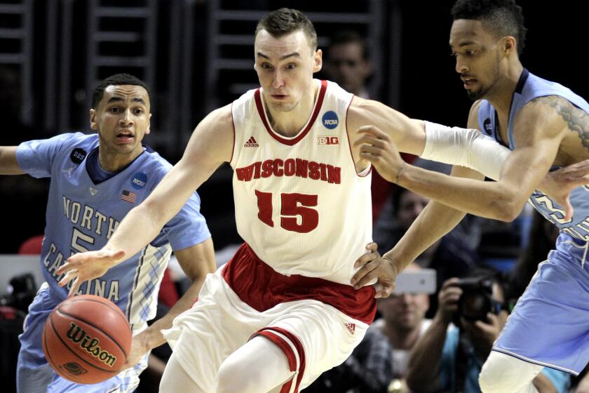 Wisconsin Badgers forward Sam Dekker dribbles away from North Carolina Tar Heels forward J.P. Tokoto, right, in the second half of the NCAA West Regional semifinal game on March 26.