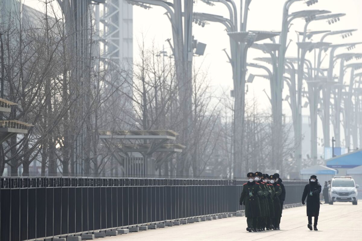 FILE - Chinese paramilitary police walk in formation on the Olympic Green near the edge of the closed-loop area at the 2022 Winter Olympics in Beijing, Jan. 30, 2022. (AP Photo/Mark Schiefelbein, File)