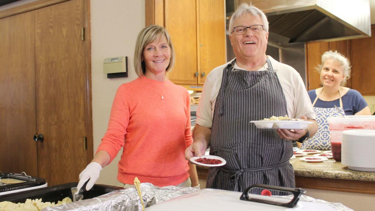 Kathy Luckie and Terry Carlson serve meals while Iris Jones volunteers in the kitchen.