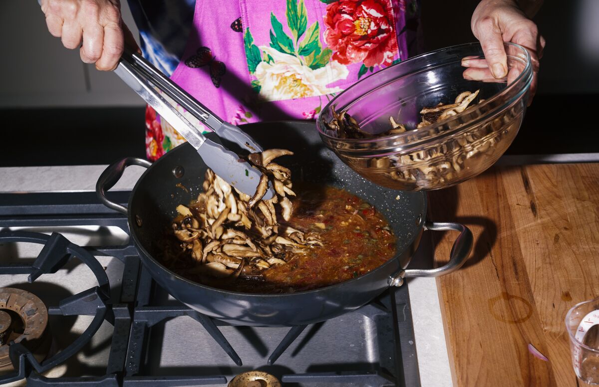 Julie Giuffrida adds mushrooms to a pan.