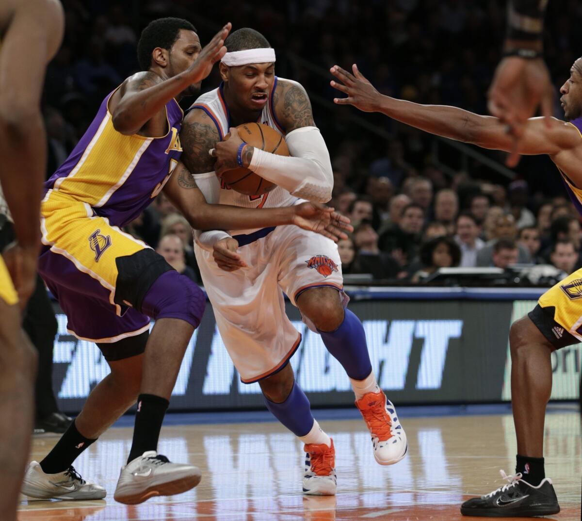 Carmelo Anthony protects the ball as he drives past Los Angeles Lakers forward Devin Ebanks.