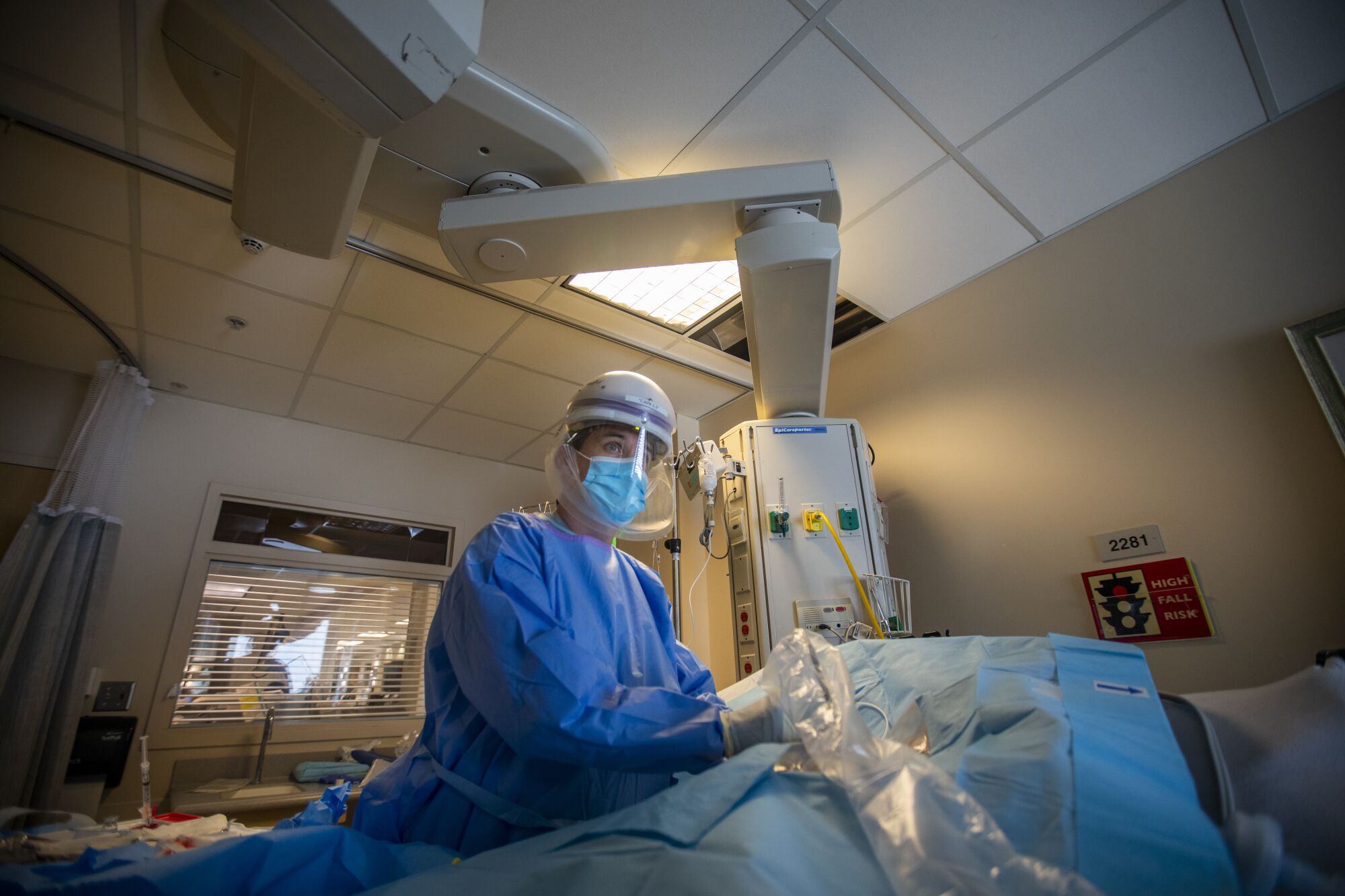 A doctor works on a patient in a bed in the ICU.