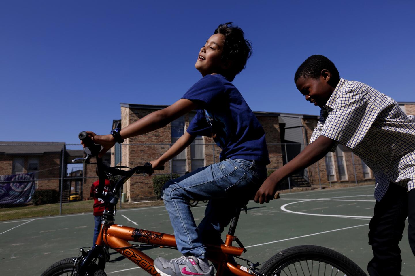 Yousef Afshoun, 7, pulls Nestor Angeta, 11, of Kongo, in Fort Worth. Yousef's father, Mohammad Afshoun, 40, fled Daraa, Syria, with wife Radieh and their six children.