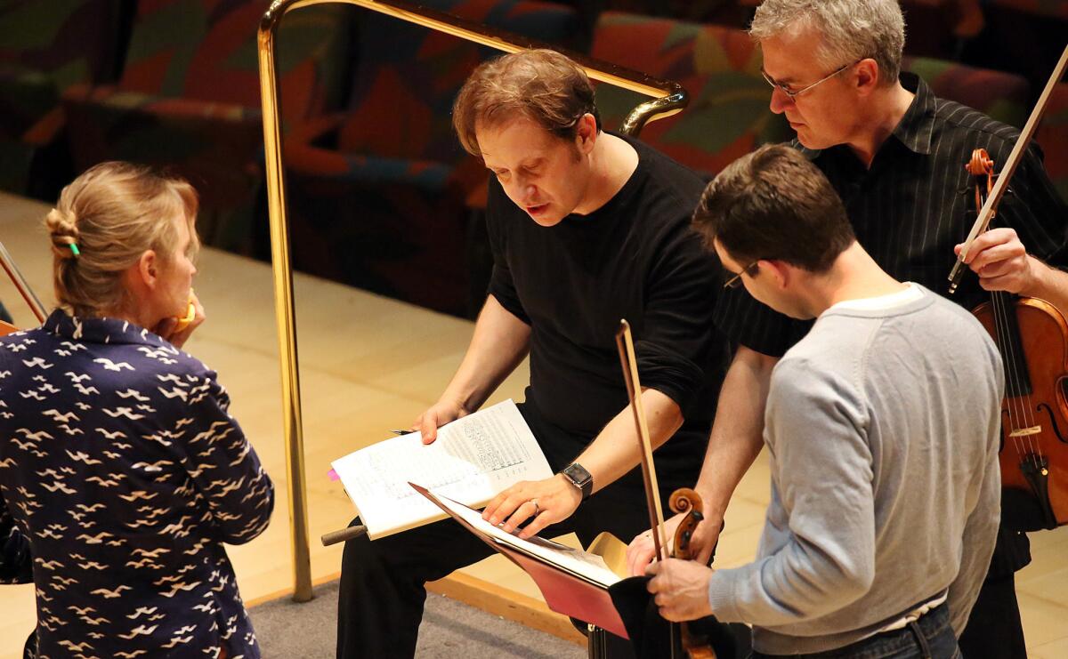 Conductor Ludovic Morlot, second from left, talks with LA Phil members Carrie Dennis, Martin Chalifour and Nathan Cole after rehearsal.