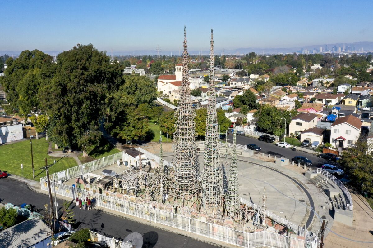 Towers rise above a neighborhood with the Los Angeles skyline in the distance.