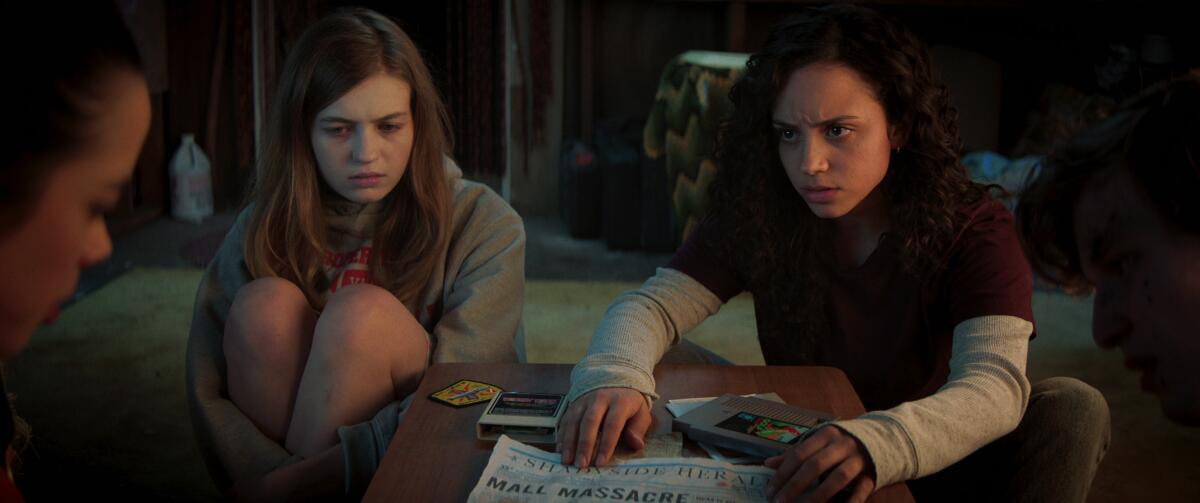 Three young people look at a newspaper.