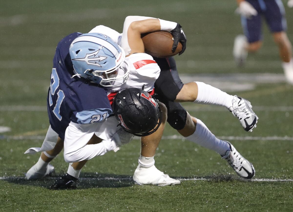 Corona del Mar's Grant Schriber (21) wrestles down San Clemente's Thomas Hartanov after a catch during Friday's game.