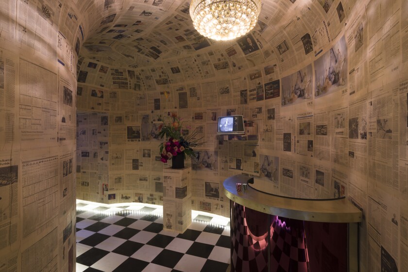 The entrance into an art show, wallpapered with newspapers.