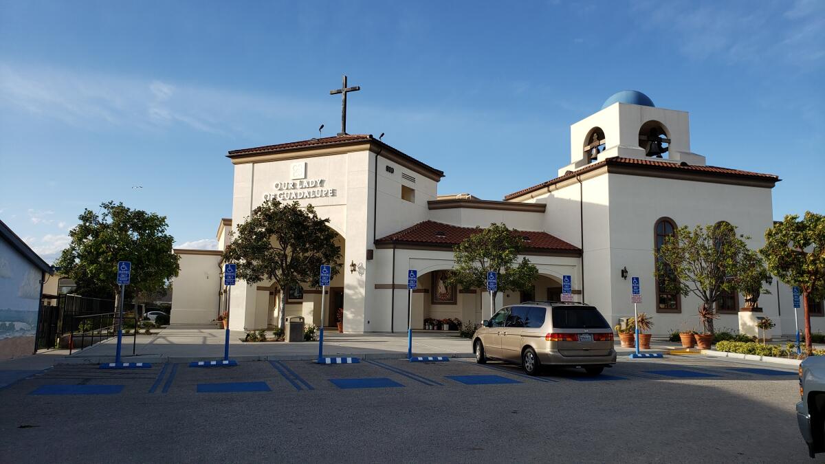 The exterior of a mission-style building with a cross on top.