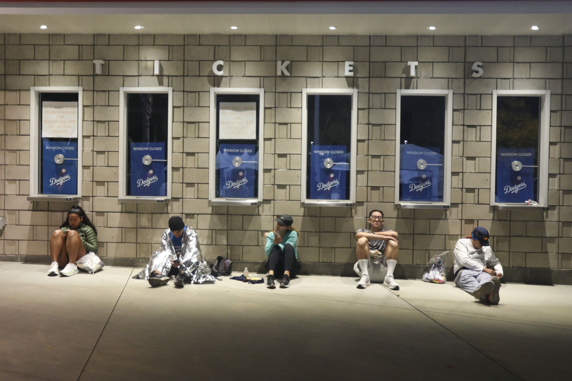 Runners sit next to a ticket booth at Dodger Stadium.