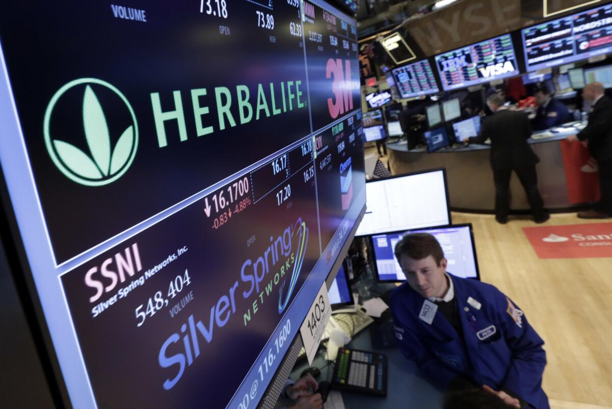 A New York Stock exchange trader stands near a video screen displaying information on companies, including Herbalife, in 2014.