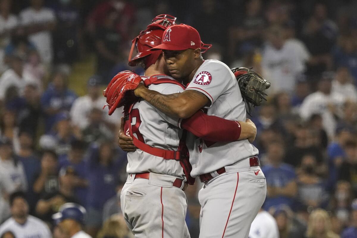 Angels closer Raisel Iglesias and catcher Max Stassi hug after a win over the Dodgers on Aug. 6, 2021.