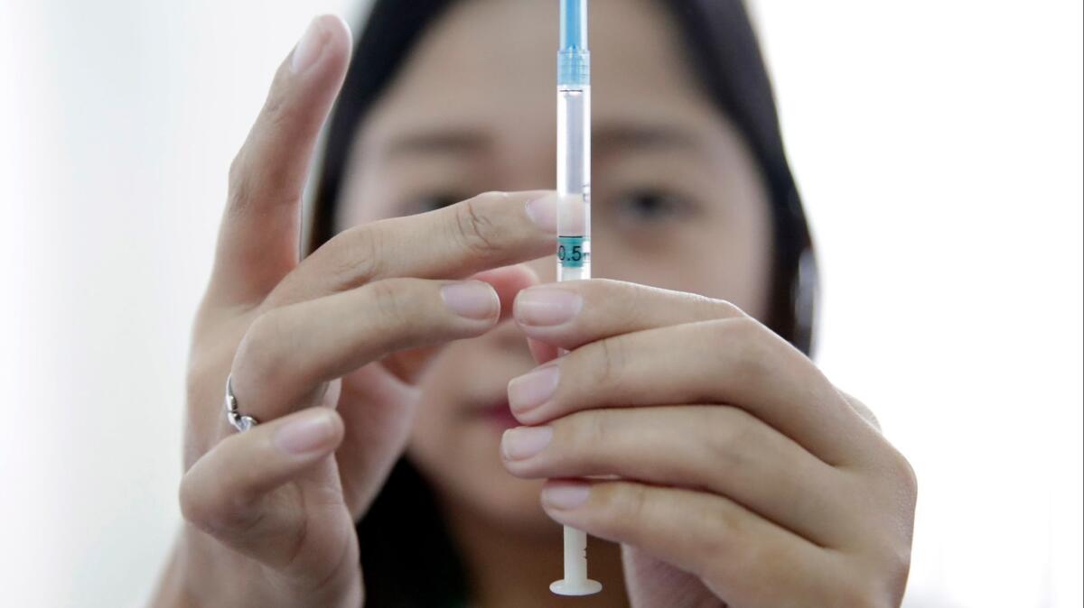 A nurse prepares a measles vaccine in the Philippines, where an outbreak has been linked to "vaccine hesitancy."