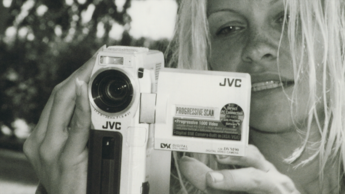Pamela Anderson holds a small video camera.