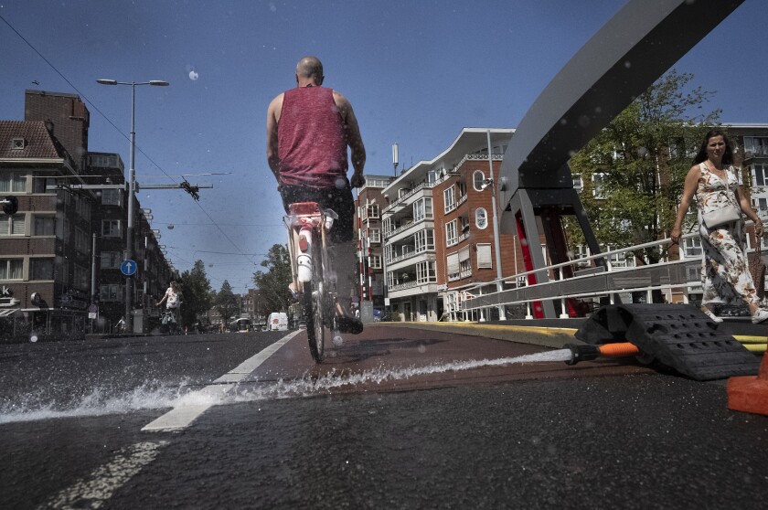 As the Dutch capital baked in the heat, municipal workers sprayed water on bridges over the city's canals to prevent metal in the constructions expanding which can jam them shut blocking boat traffic, in Amsterdam, Tuesday, July 19, 2022. (AP Photo/Peter Dejong)