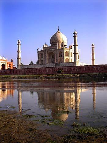 Shimmering on the banks of the Yamuna River, the marble Taj Mahal is an architectural spectacle, its symmetry  four minarets and matching mosques on two sides  enhanced by its reflection on the water. Because worshipers must face east, only one of the mosques is functional; the other was duplicated for purposes of symmetry.