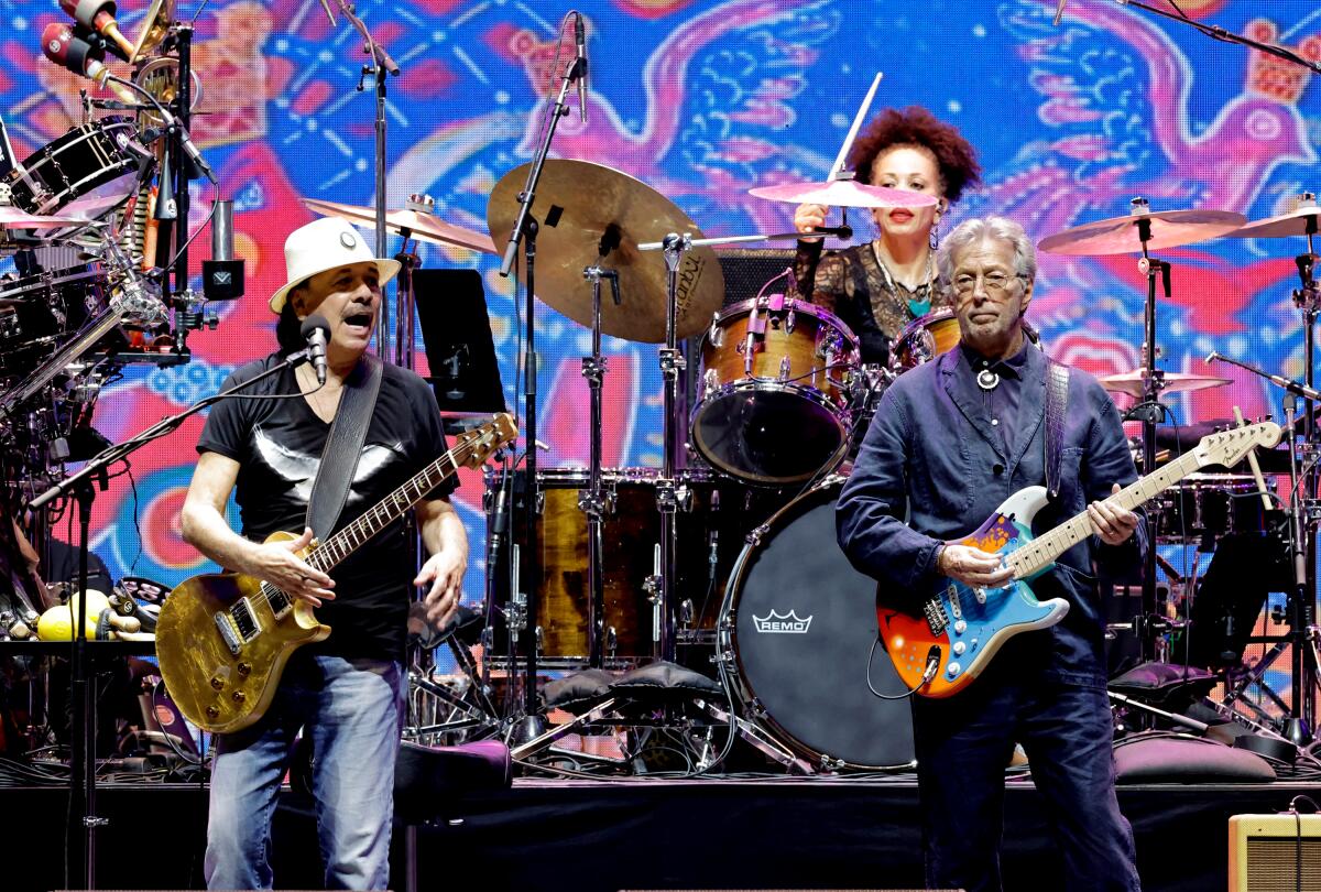 Carlos Santana and Eric Clapton playing electric guitars onstage