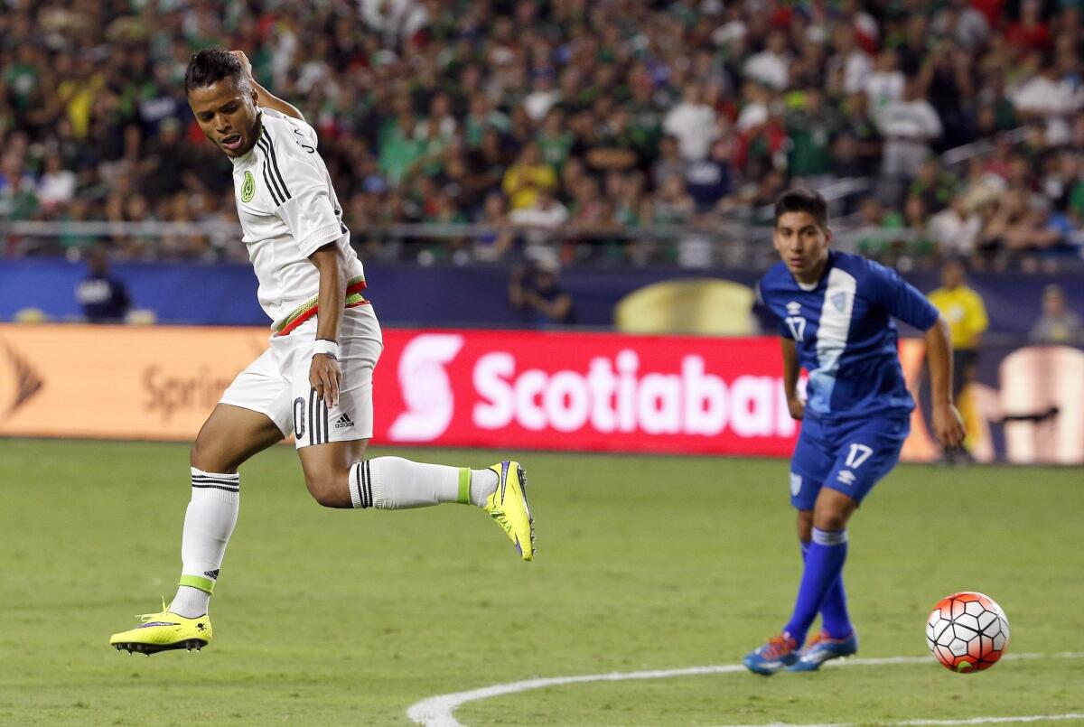 Mexico forward Giovani Dos Santos, left, passes the ball behind him and past Guatemala midfielder Brandon De Leon in the Gold Cup.