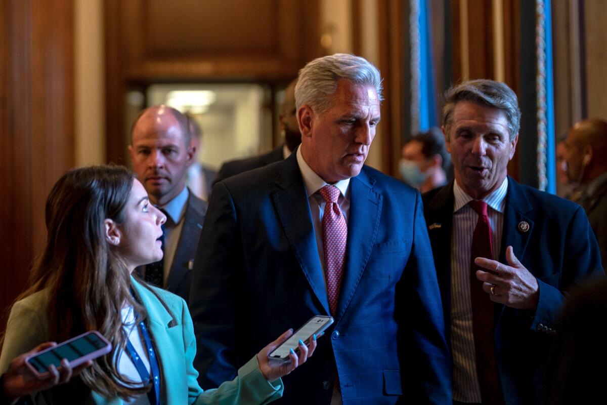 House Minority Leader Kevin McCarthy walks through a hallway with reporters nearby