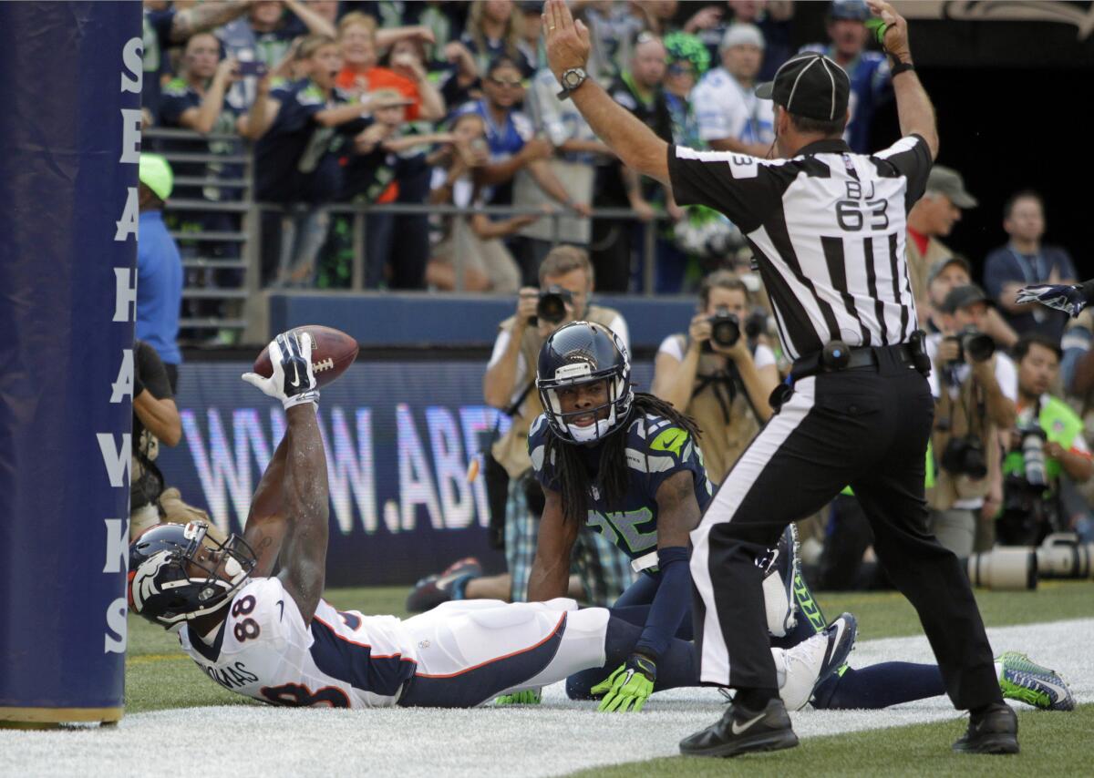 Denver wide receiver Demaryius Thomas makes a game-tying two-point conversion as Seattle cornerback Richard Sherman looks on and back judge Jim Quirk makes the call on Sept. 21.