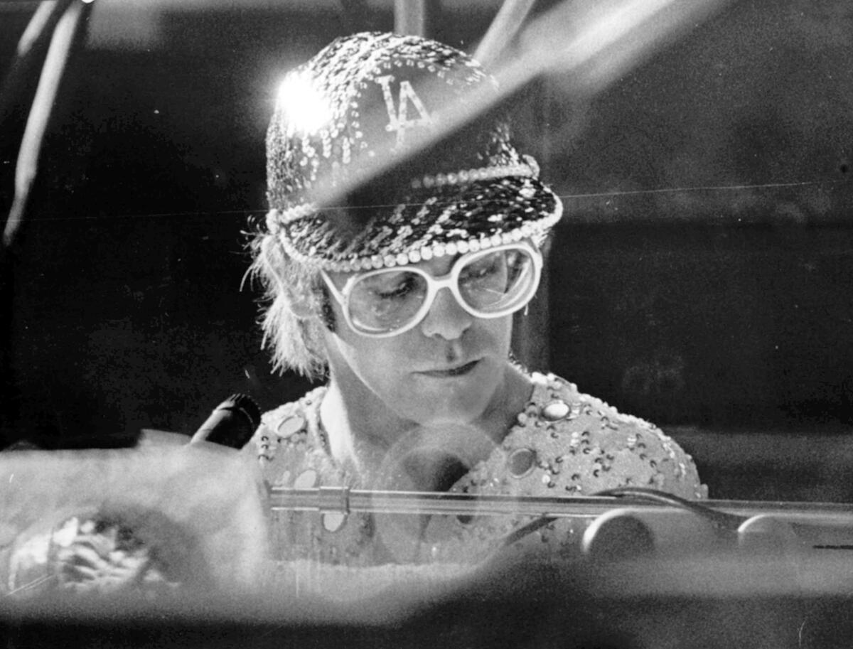 Closeup of a man in large round glasses and a sparkling baseball hat that says "L.A."