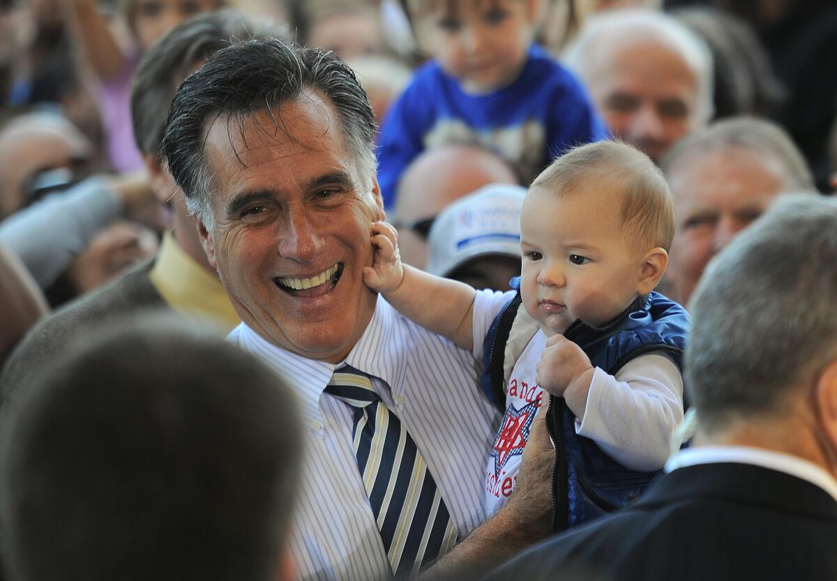 Mitt Romney holds a supporter's baby during a rally at Landmark Aviation in Tampa, Fla.