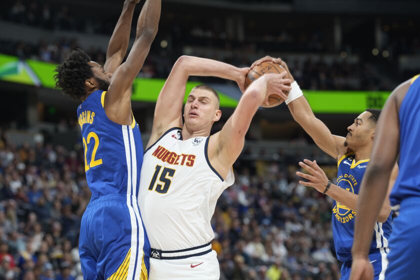Denver Nuggets center Nikola Jokic, center, loses control of the ball as Golden State Warriors forward Andrew Wiggins, left, and guard Jordan Poole defend in the first half of an NBA basketball game Thursday, Feb. 2, 2023, in Denver. (AP Photo/David Zalubowski)