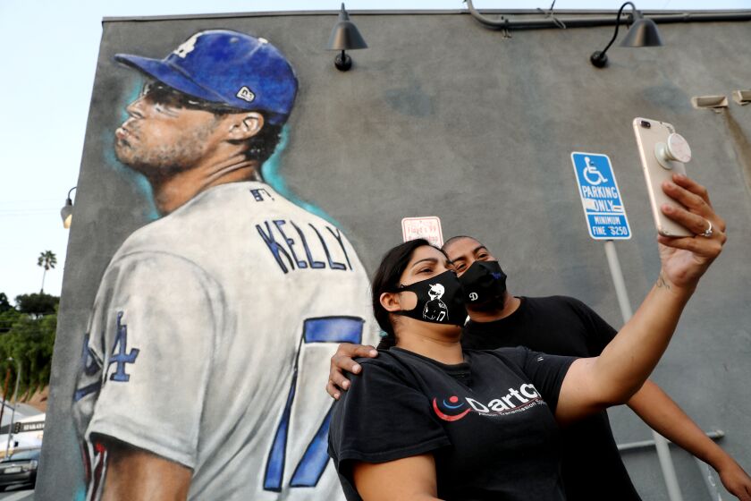 LOS ANGELES, CA - SEPTEMBER 09: Ana and Brian Garcia take a selfie with the Los Angeles Dodgers pitcher Joe Kelly pouty face mural painted on the side of the Floyd's 99 Barbershop in Silver Lake, less than two miles from Dodger Stadium just in time for Astros series on Wednesday, Sept. 9, 2020 in Los Angeles, CA. (Gary Coronado / Los Angeles Times)