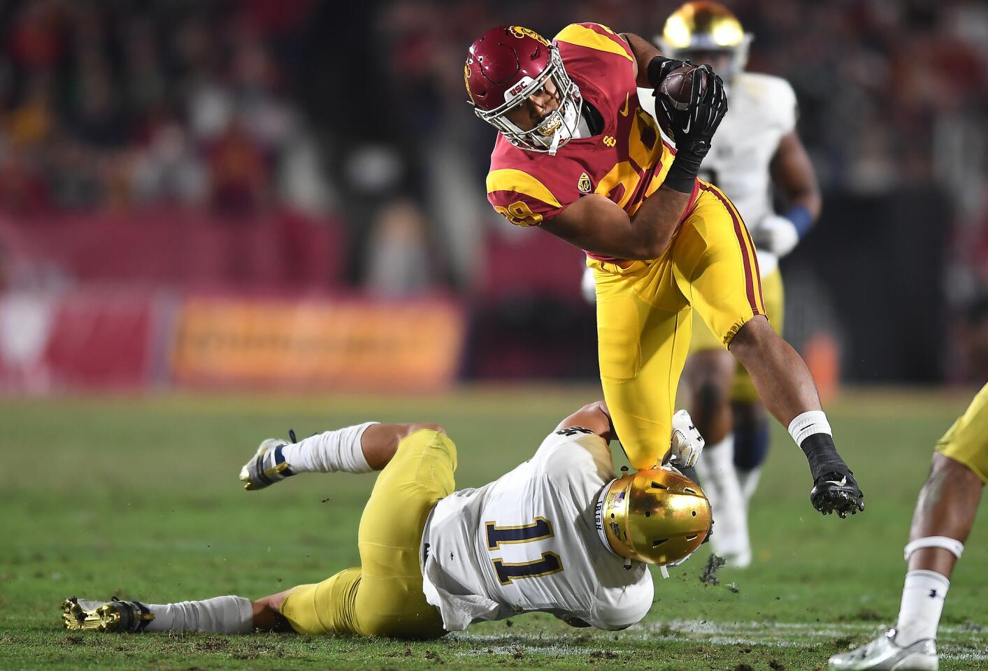 USC running back Vavae Malepeai picks up yards over Notre Dame's Aldi Gilman at the Coliseum.