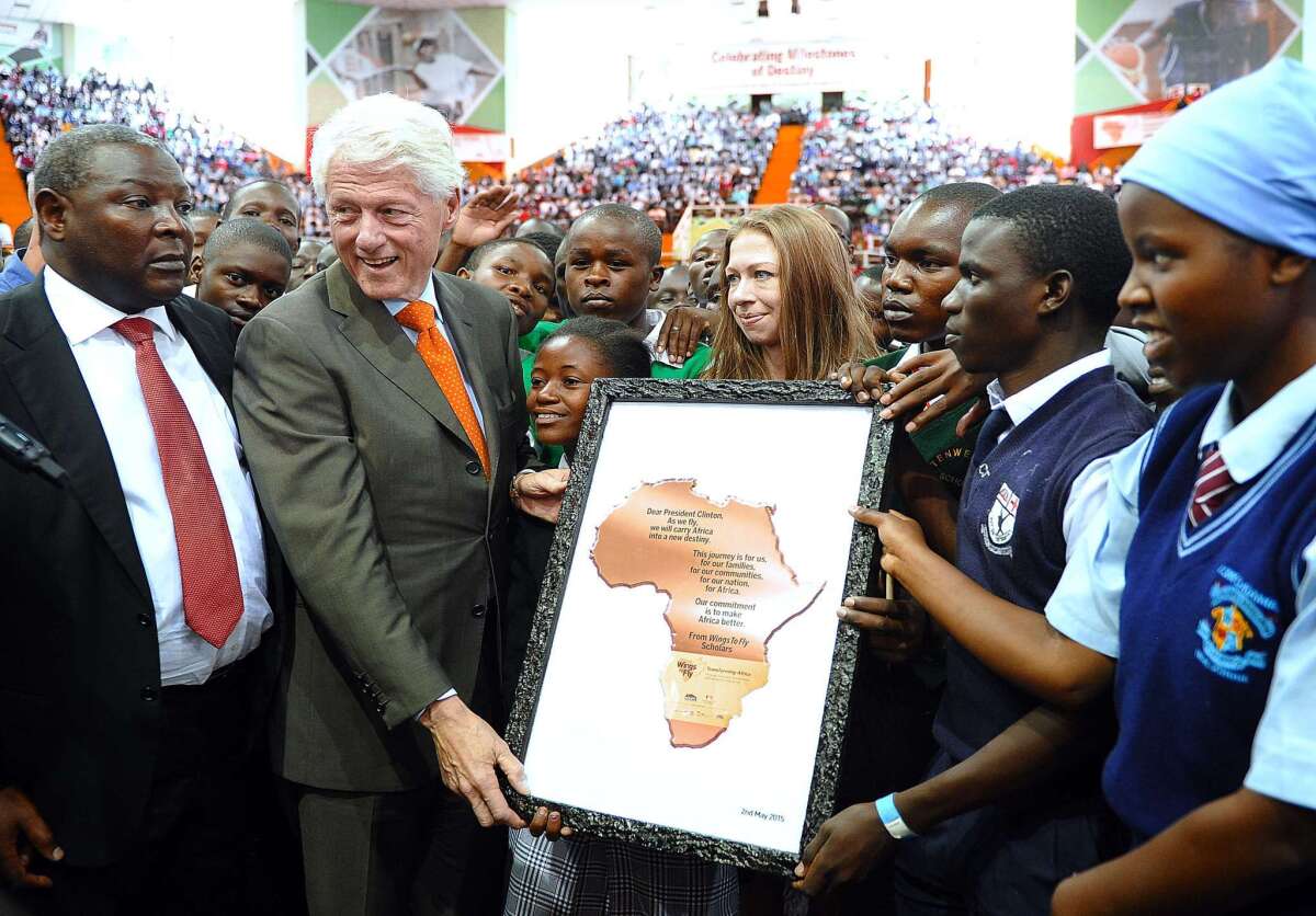 Former President Clinton receives an award certificate from students on Saturday in Nairobi.