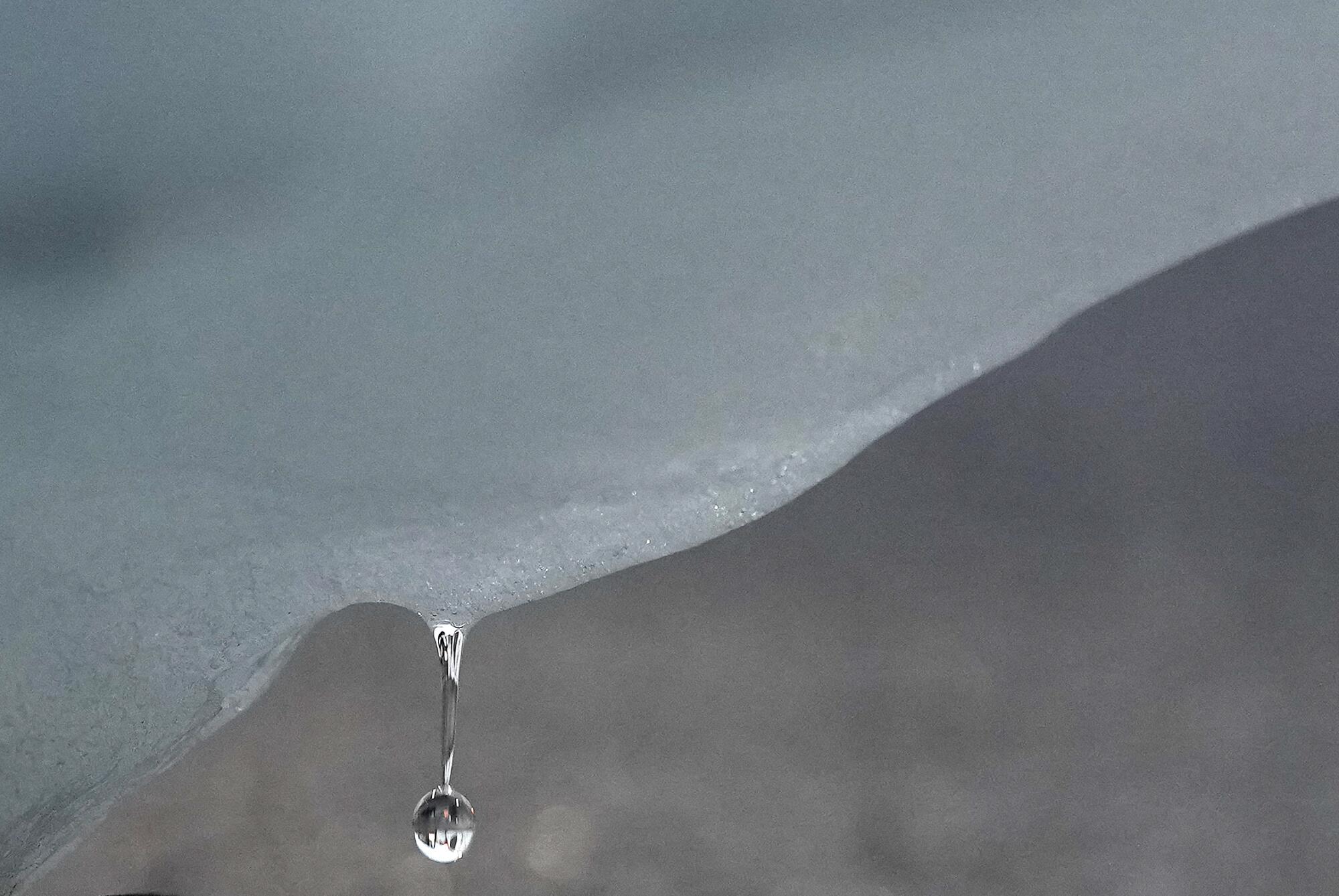 A droplet of water falls from an iceberg.