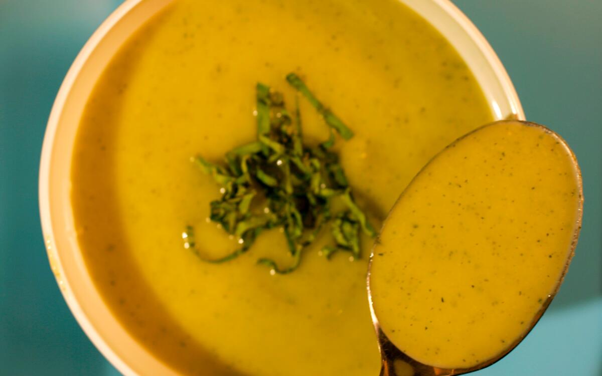 A creamy Zucchini soup garnished with fresh basil.