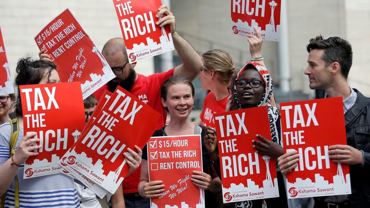 Demonstrators display signs in support of Seattle's new city income tax on wealthy residents.