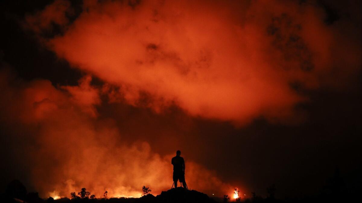 A man photographs lava erupting from Kilauea.