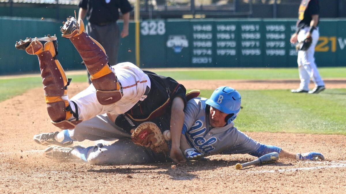 UCLA outfielder Ty Moore's hard slide takes USC catcher Garrett Stubbs off his feet and knocks the ball free on a play at the plate in the sixth inning. The Bruins won 8-3.