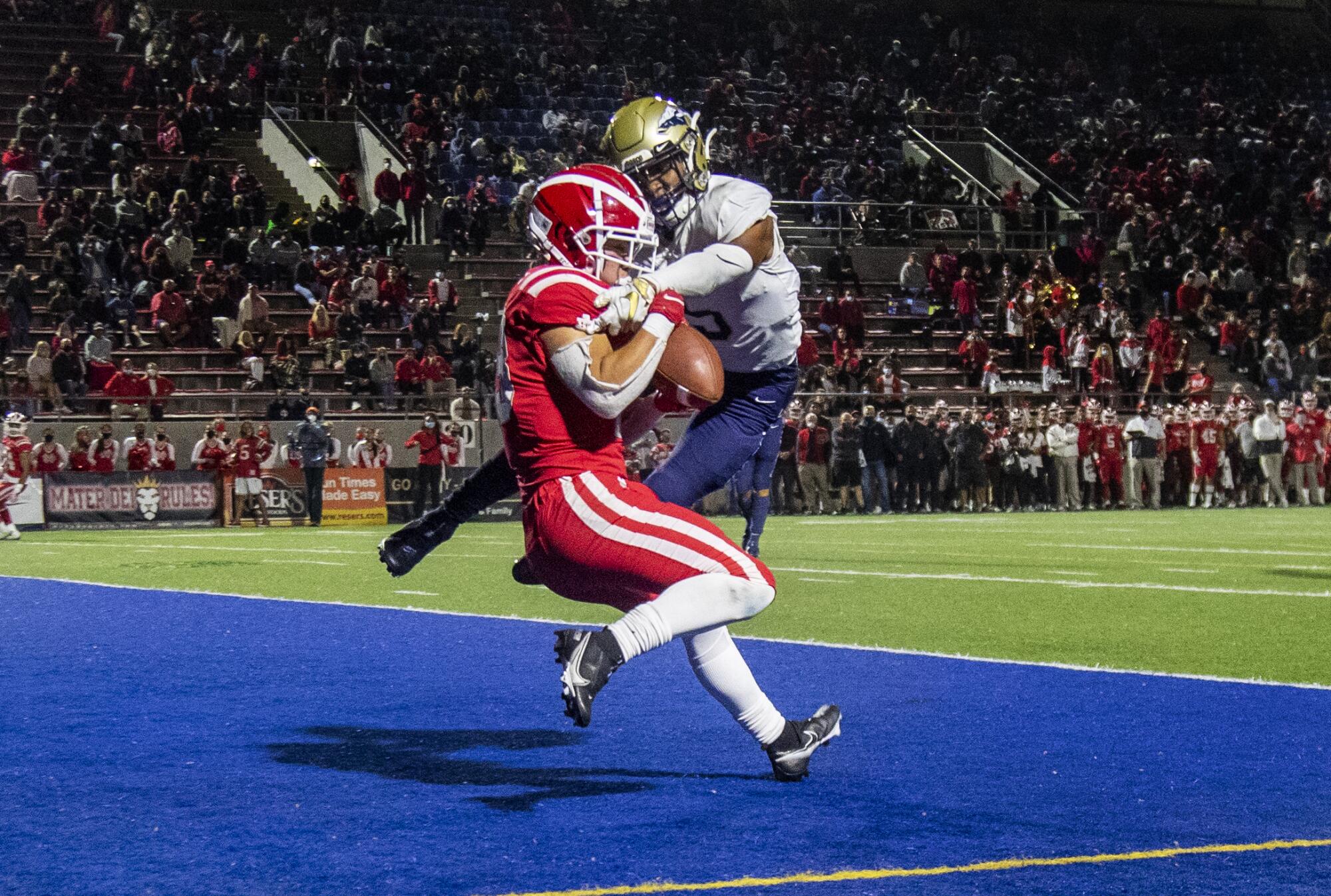Mater Dei receiver Josiah Zamora hangs on to make a touchdown catch while defended by St. John Bosco's Jaxon Harley.