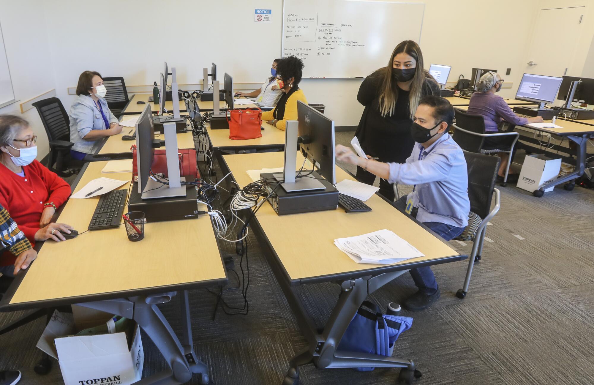 Election worker Cassandra Ramirez works with Jonathan Borja on verifying ballot signatures.