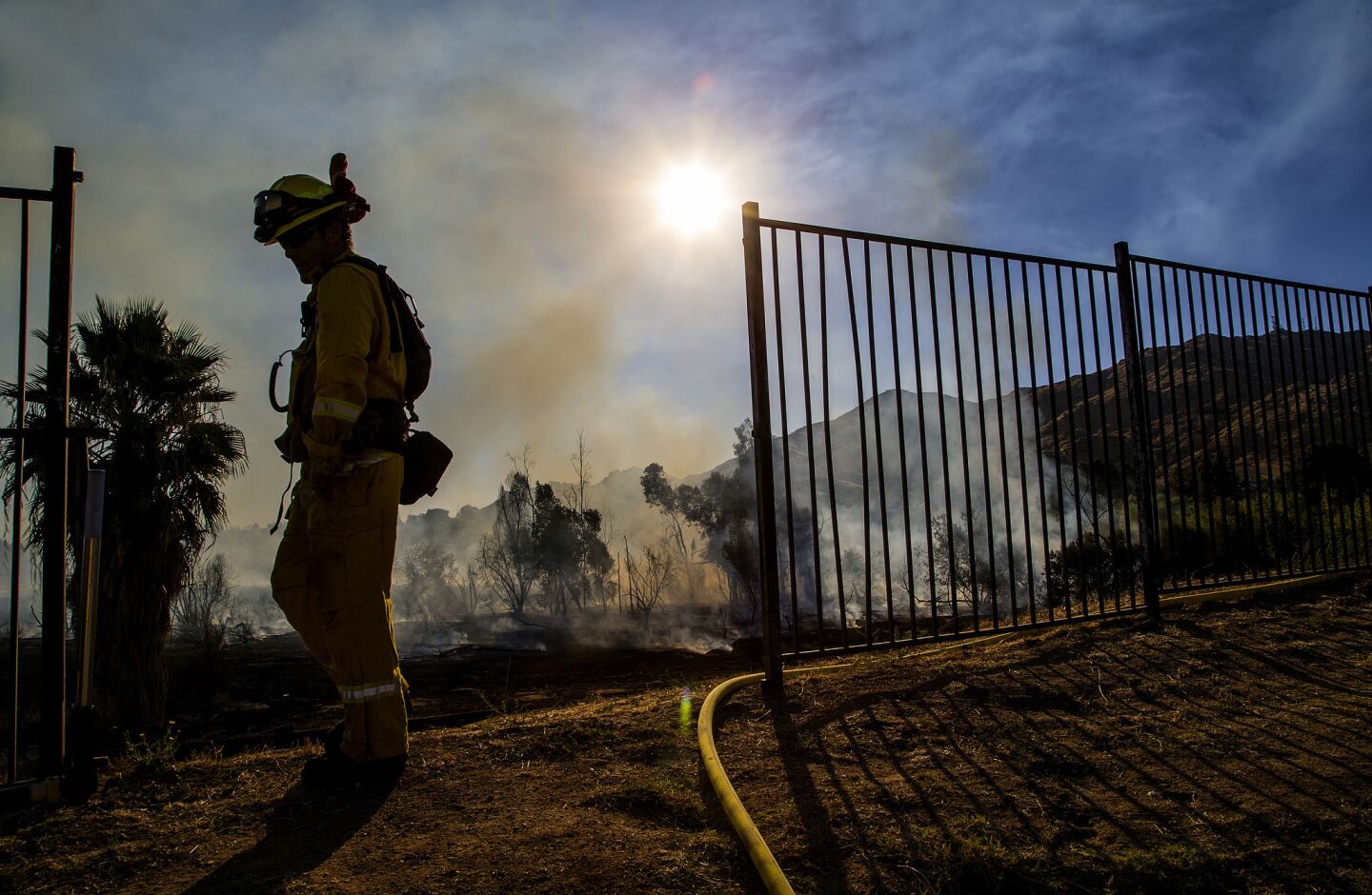 A firefighter keeps watch on a wildfire burning behind homes at Poorman's Reservoir in Moreno Valley.