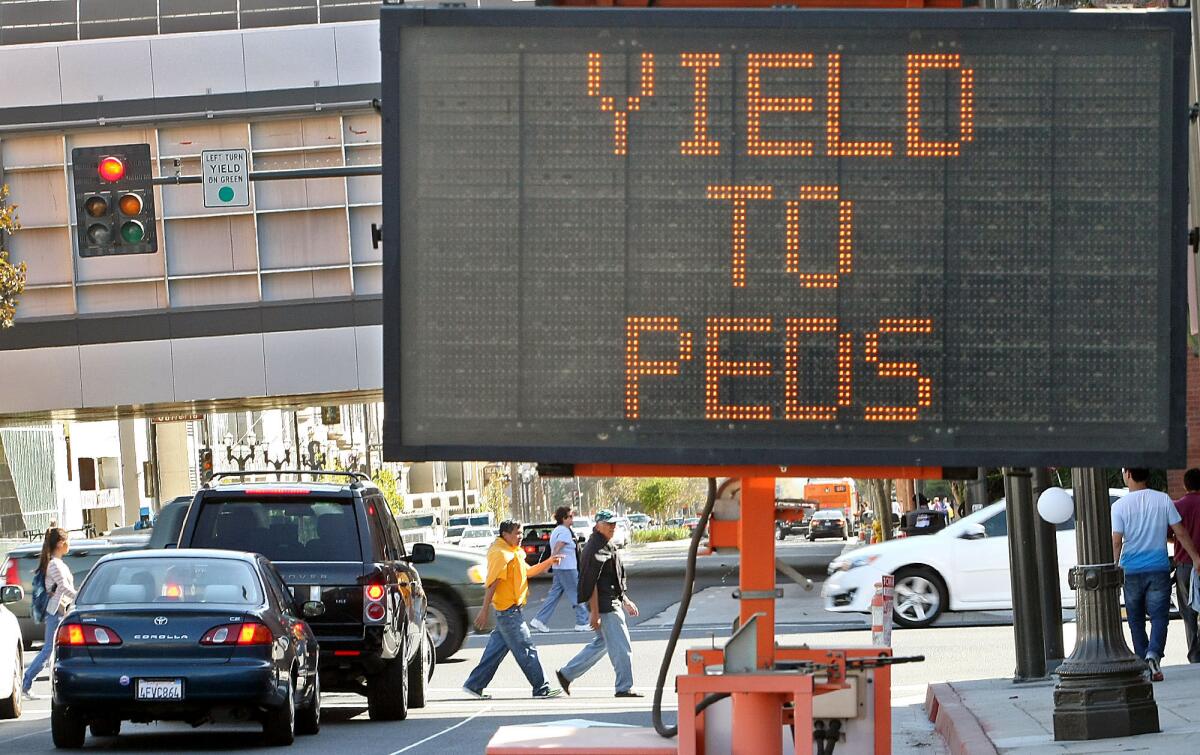 Pedestrians cross the intersection of Broadway and Central Avenue near a sign instructing drivers to yield to pedestrians on Friday, Oct. 4, 2013.