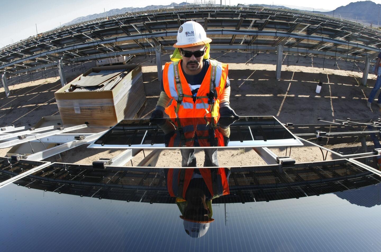 Adrian Pacheco installs a photovoltaic panel at the Tenaska Imperial Solar Energy South project in the Imperial Valley west of El Centro, Calif.