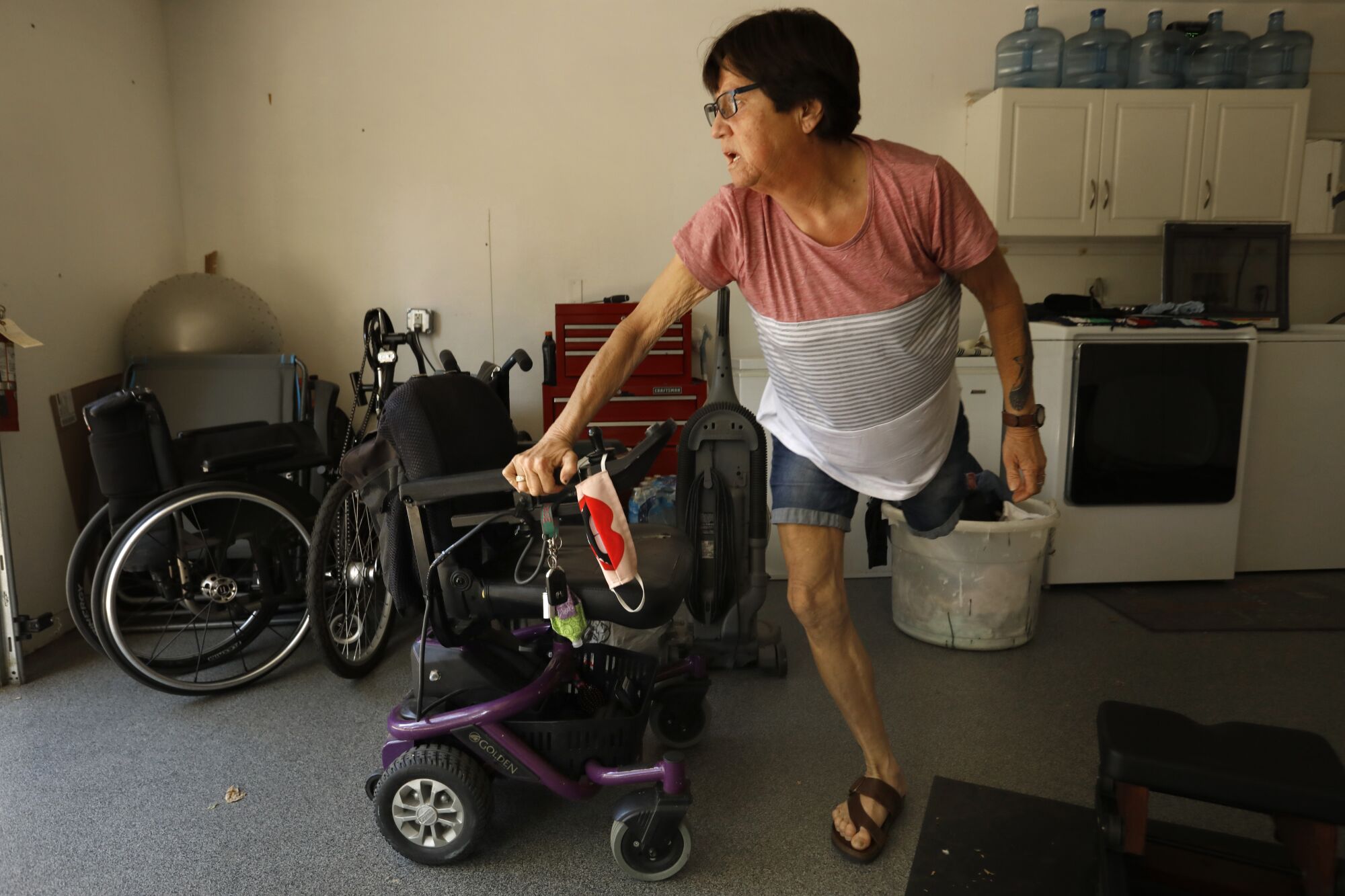 A woman with one leg stands next to a motorized wheelchair