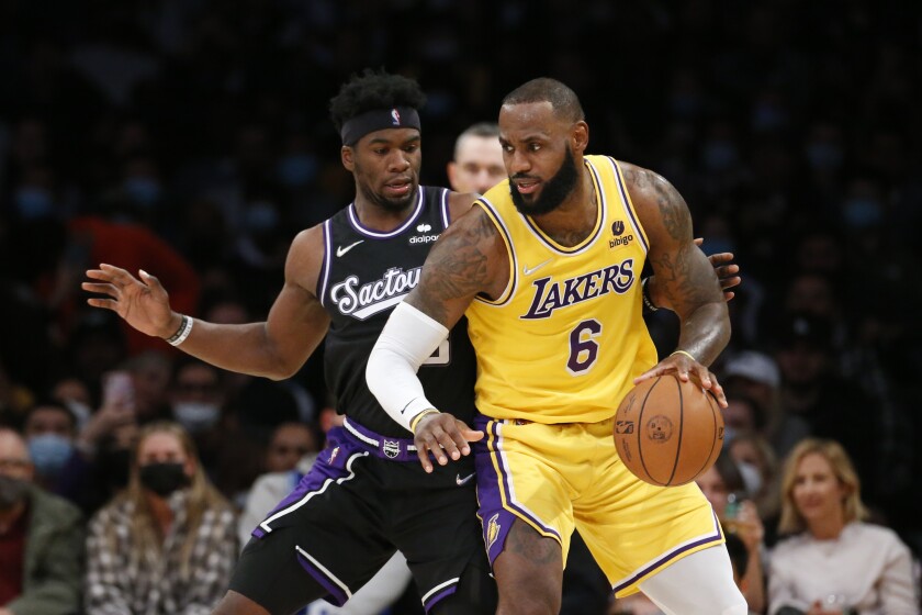 Lakers forward LeBron James, right, controls the ball in front of Sacramento Kings guard Terence Davis II.